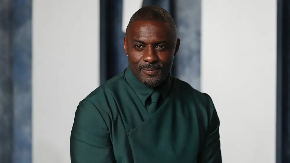 Idris Elba posant avec élégance dans un costume vert, regard confiant et charismatique, lors d'un événement officiel.