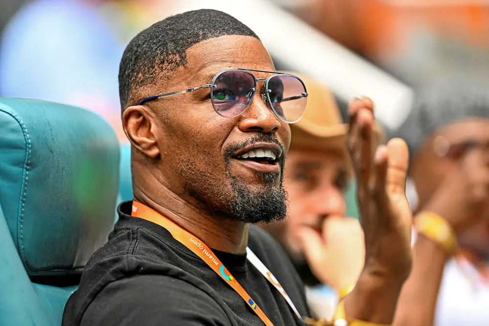 Jamie Foxx souriant, avec des lunettes de soleil, représentant son charisme et sa stature en tant qu'acteur primé et artiste polyvalent.