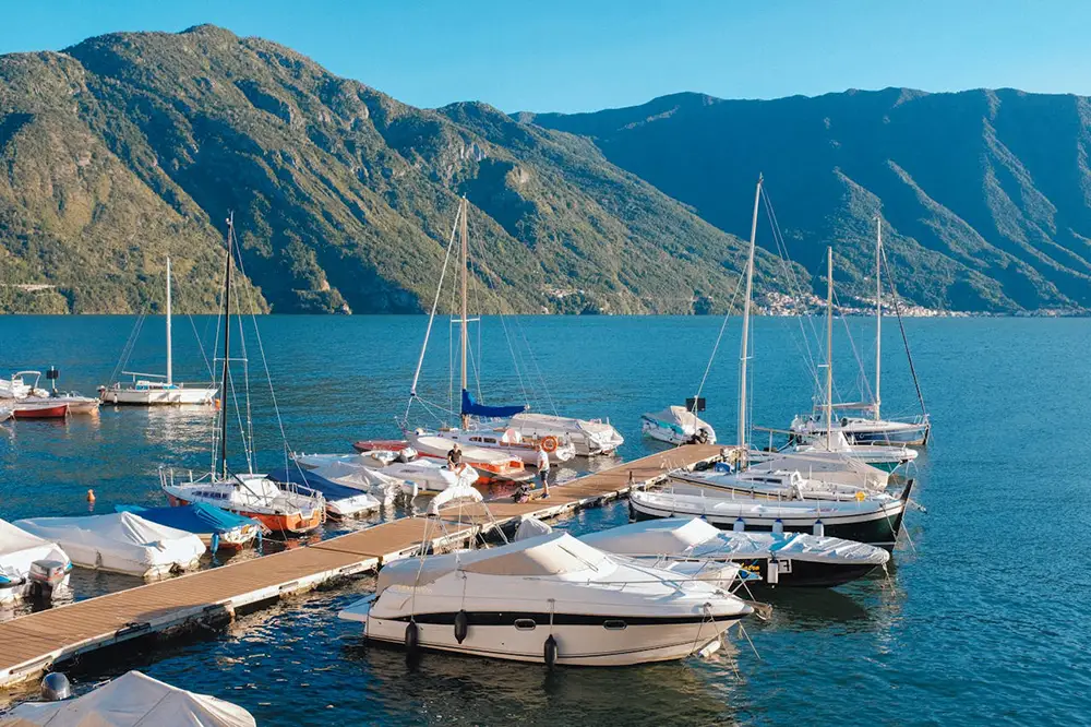 Petite marina de bateaux amarrés au ponton, sur un lac entouré de montagnes