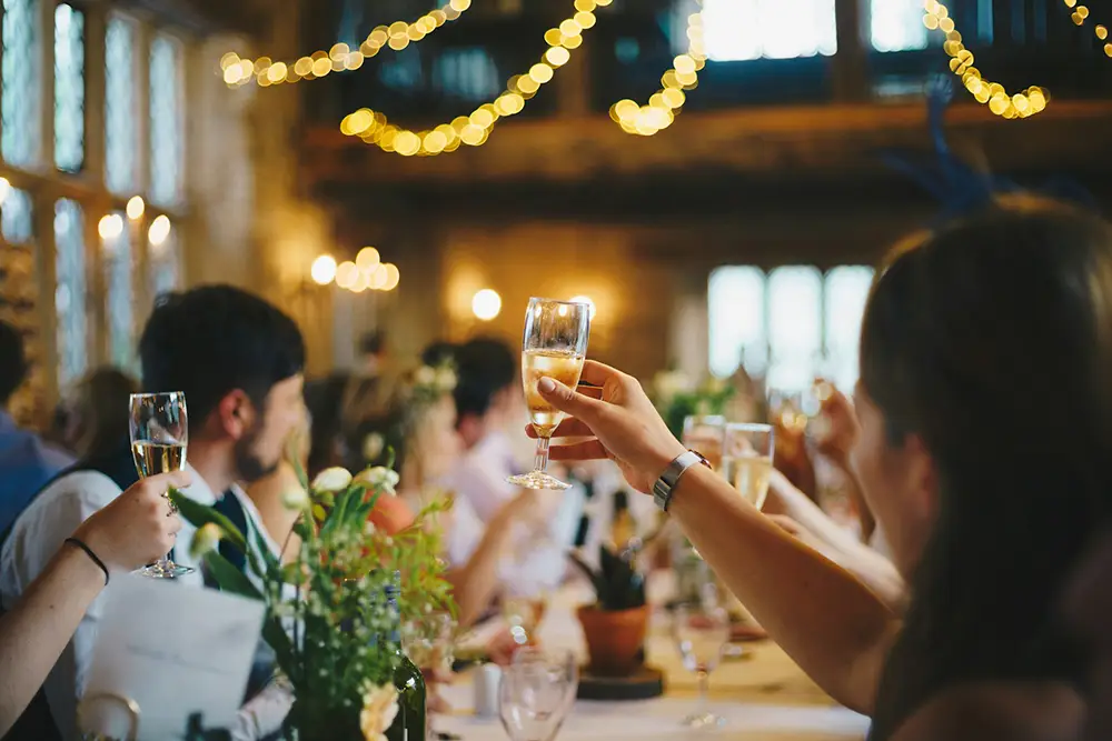 invités du mariage levant leur coupe de champagne à la santé des mariés lors du repas