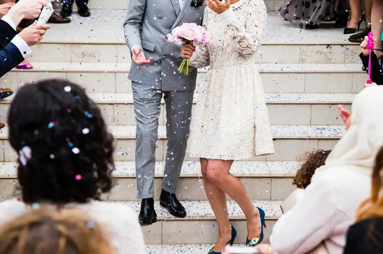 Jeunes mariés sortant de l'église après la cérémonie de mariage et descendant les escaliers sous les confettis.