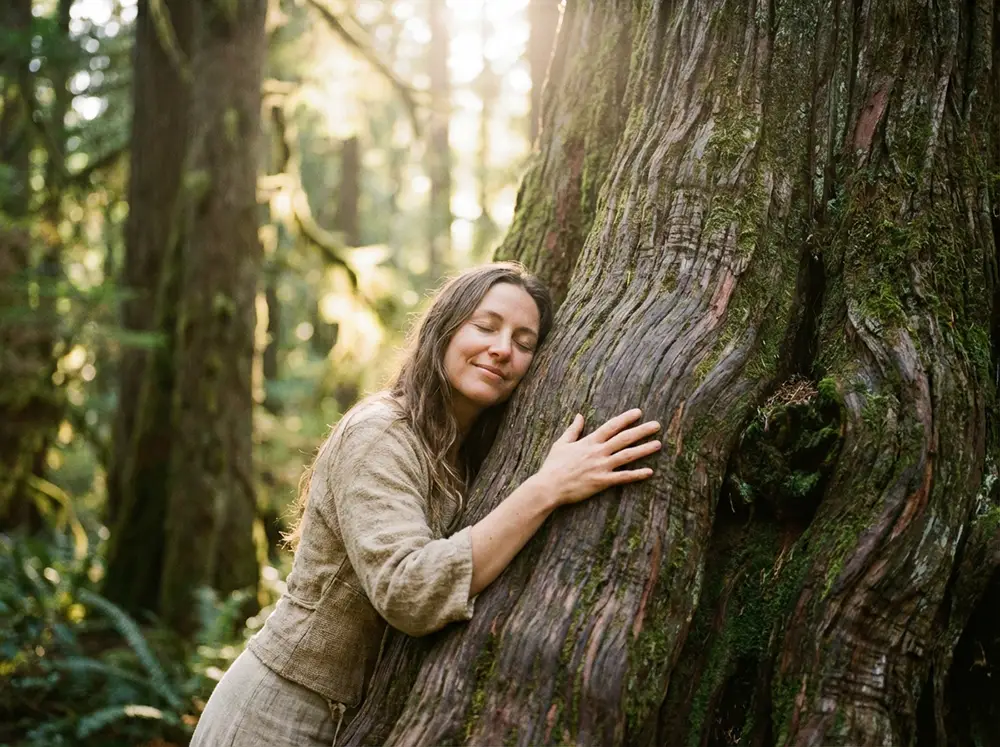 Personne enlaçant tendrement un grand arbre majestueux, joue contre écorce rugueuse, expression de connexion émotionnelle et gratitude, mains caressant le tronc, lumière tamisée de forêt enchantée, ambiance spirituelle douce et bienveillante