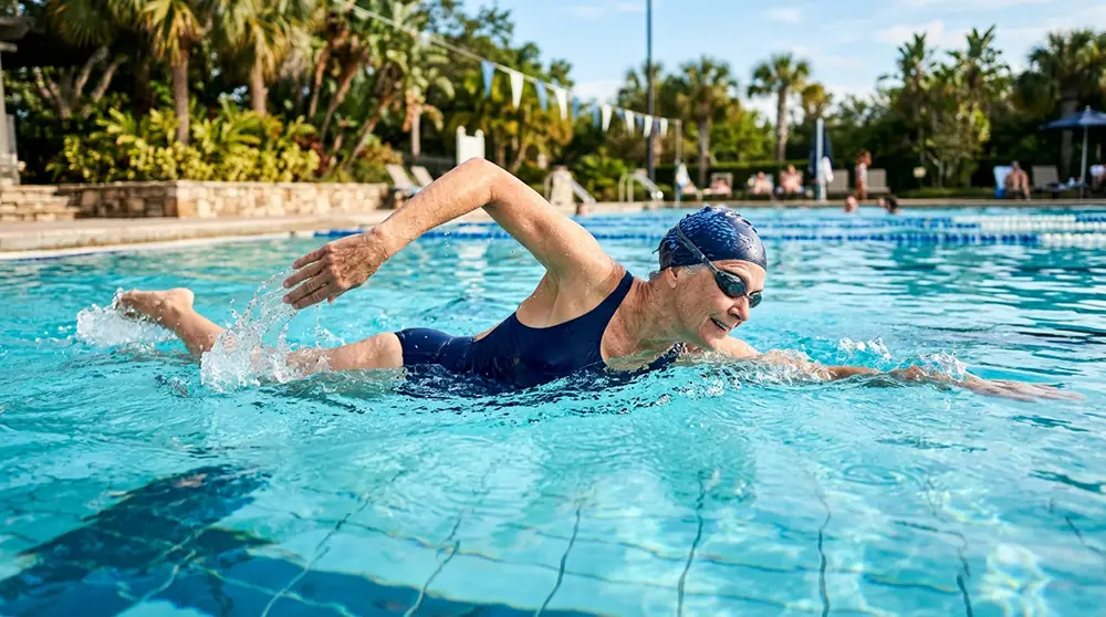 Femme de 65 ans qui nage le crawl dans une piscine extérieure ensoleillée
