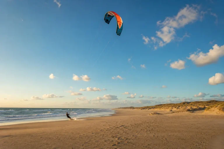 Kitesurfeur en action sur une plage atlantique française avec son aile colorée dans le ciel